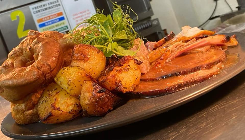 Sunday roast at The George — Yorkshire pudding, roast potatoes and crisp pork with pea-shoot garnish
