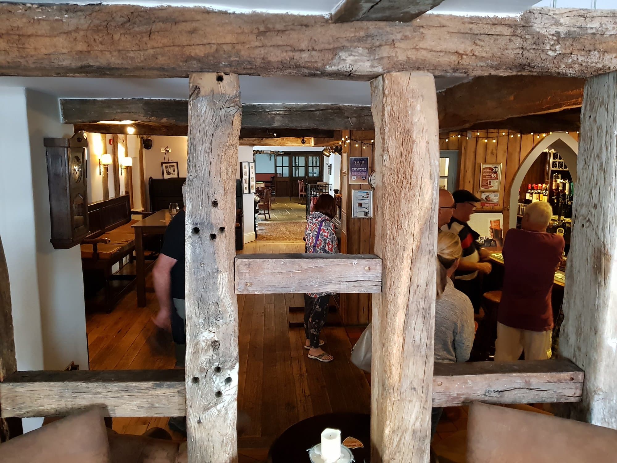 Inside The George Inn — view through heavy timber beam pillars to the bar and team welcoming guests