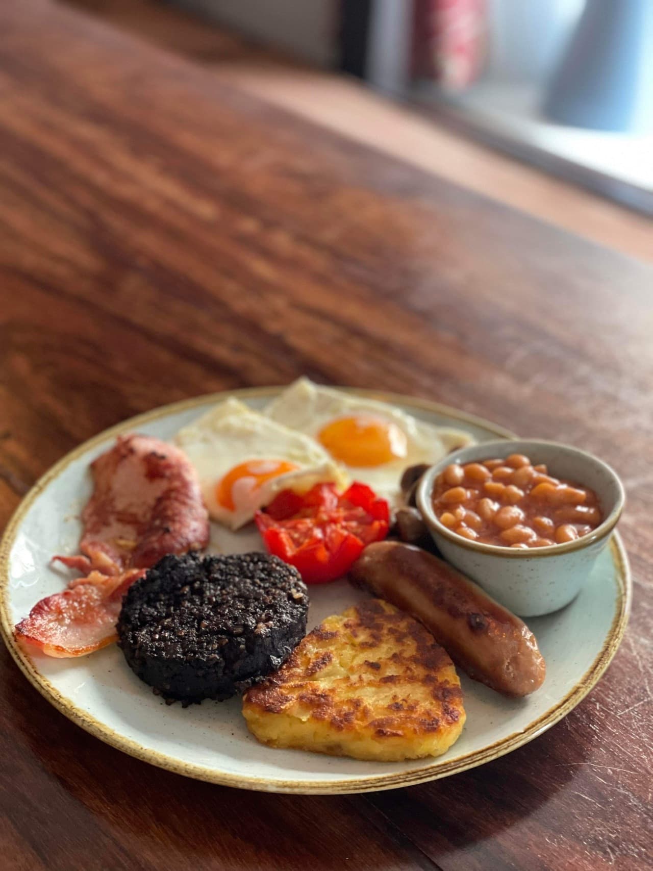 Full English breakfast at The George — bacon, sausage, fried eggs, black pudding, hash brown and baked beans on a stoneware plate