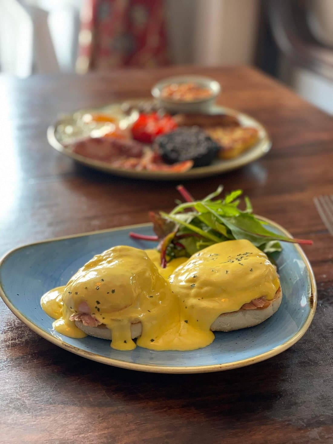 Eggs Benedict at The George — poached eggs and ham on a toasted muffin with hollandaise sauce, side salad and a full English breakfast in the background