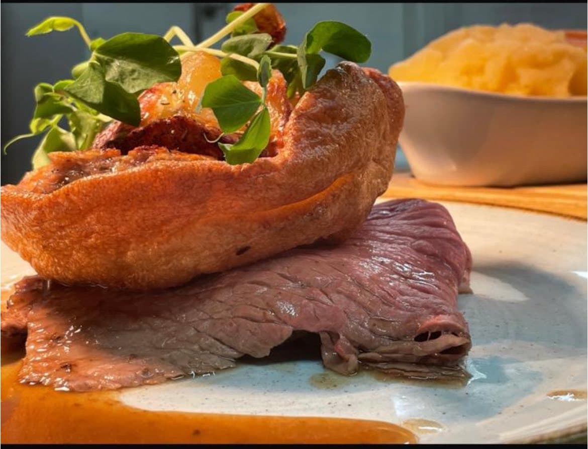 Sunday roast beef with a Yorkshire pudding cup of roast potatoes, pea shoots and gravy