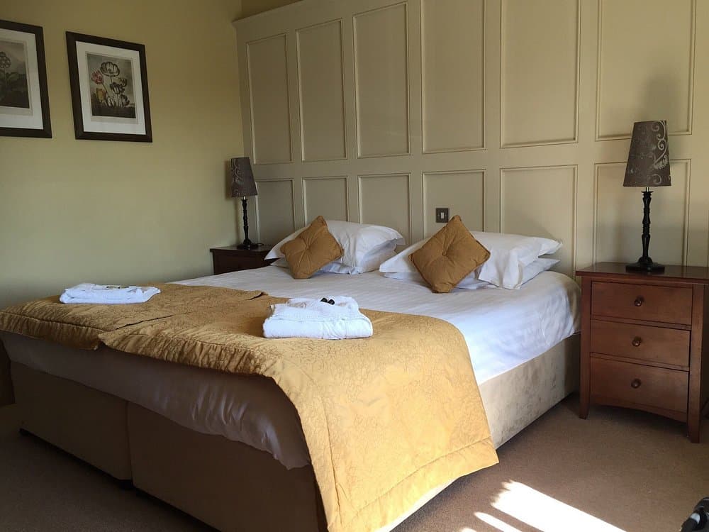 Classic Double room at The George Inn — cream panelled feature wall, gold bedspread, white towels prepared on the bed