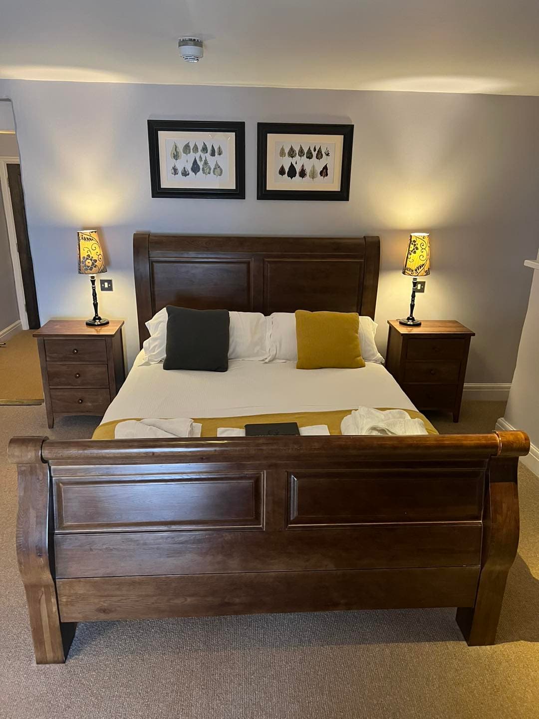 Double-or-Twin room at The George Inn — dark mahogany sleigh bed with mustard and charcoal cushions, matching bedside tables and patterned lamps