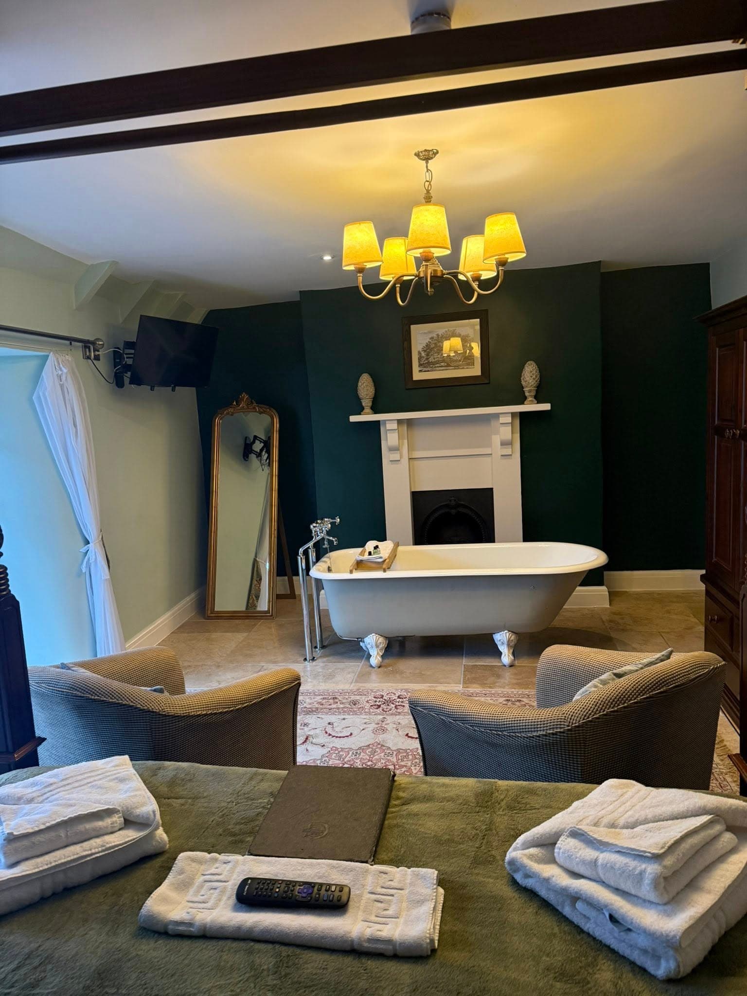 Superior Four-Poster room at The George Inn — view from the bed to a free-standing roll-top bath in the room, marble fireplace, brass chandelier and prepared towels