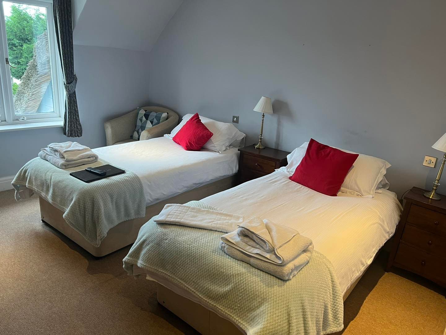 Economy Twin room at The George Inn — twin beds with crisp white linens, red accent cushions and sage throws
